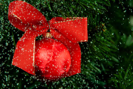 Red christmas ball hanging on the tree and falling snow.の写真素材