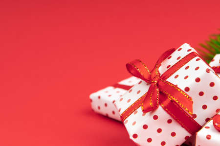 Heaps of new year gifts wrapped in gift paper polka with festive ribbon on red background with copy space.の写真素材