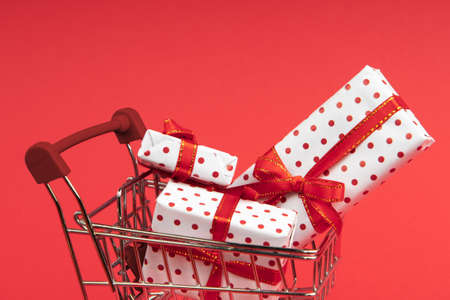 Grocery cart full of gifts on red background with copy space.の写真素材