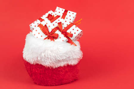 Heaps of christmas gifts in Santa Claus sack wrapped in gift paper polka with festive ribbon on red background with copy space.の写真素材