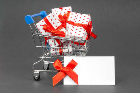 Grocery cart full of gifts on a dark gray background with place for text mock up. Black Friday and holidays concept.の写真素材