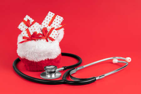 Santa claus bag full of gifts with stethoscope on red background with copy space. Medicine concept.の写真素材