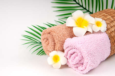 Pastel towels with Plumeria flowers with tropical palm leaves on light background with copy space. Skin care and spa concept.の写真素材