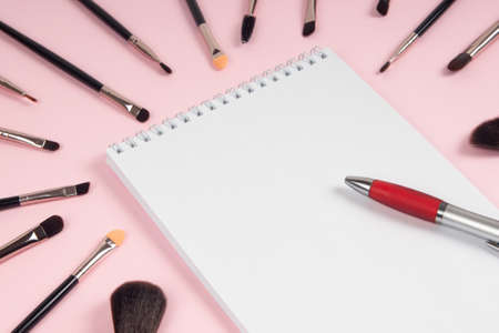 Large set of makeup brushes with a notebook and pen mock-up on  pinkの写真素材