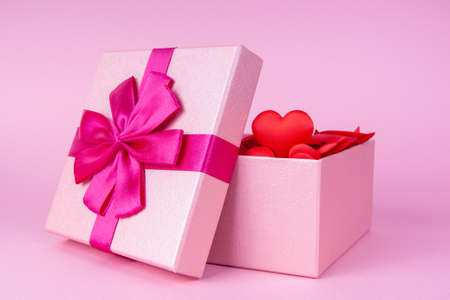 Open gift with heart inside on pink background with place for text, concept of valentine's day, anniversary and romance.の写真素材