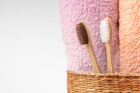 Bamboo toothbrushes with towels in a wicker wooden basket with copy space on white background. Spa, healthy lifestyle and ecology concept.の写真素材