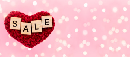 Banner word sale on red plush heart blurred pink background with copy-space with beautiful bokeh from garlands lights. Concept holidays black friday, christmas, valentine's day and seasonal discountsの写真素材