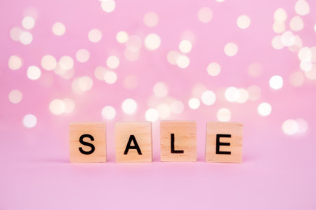 Words Sale on a blurred pink background with beautiful bokeh garland lights. With copyspace Concept of holidays christmas, valentine's day, black friday, mothers day and seasonal discountsの写真素材