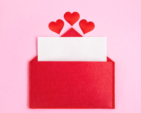 Red open envelope with a sheet of paper with a hearts on a pink background with mock-up. Valentines day holidays concept and love notes, christmas and new year letters for Santa Clausの写真素材
