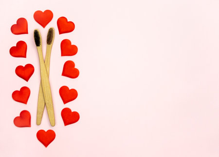 Flat lay composition with hearts shape with bamboo toothbrushes and space for text on pink background, top view. Ecology concept with healthy lifestyle.の写真素材