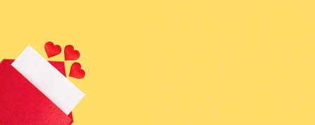 Banner red open envelope with a sheet of paper with a hearts on a yellow background with mock-up. Valentines day holidays concept and love notes, christmas and new year letters for Santa Claus.の写真素材