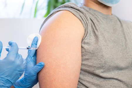 Close up of a Doctor making a vaccination in the shoulder of patient. Concept of injections, vaccinations, fight against  virus,   health care and medicine.の写真素材