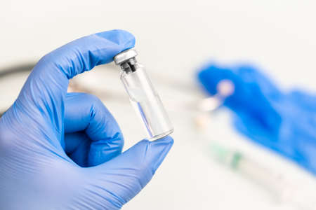 Ampoule for internal injection in the hands of a doctor in medical gloves, with syringe, blurred background of a medical worker. Vaccination concept, , medicine and health.の写真素材