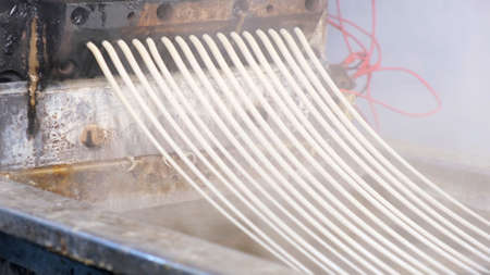 Recycled molten plastic comes out of the extruder machine Concept of recycling, plastic, industry, factories. Continuous extrusion with cooling in water to be processed into a pellet.の写真素材