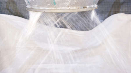 White hard grinded plastic comes out of the cyclone of the machine by pneumatic transport into the big bag. concept of recyclable materials, plastic recycling, pellet production plantsの写真素材
