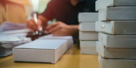 Unrecognizable person labeling white carton boxes for shipment, preparing customer orders for delivery, illustrating efficient logistics and fulfillment for online retail businessesの素材