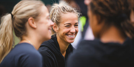 Three casual women engaging in a lively outdoor conversation, with one woman joyfully smiling and laughing while connecting with friends in a relaxed settingの素材
