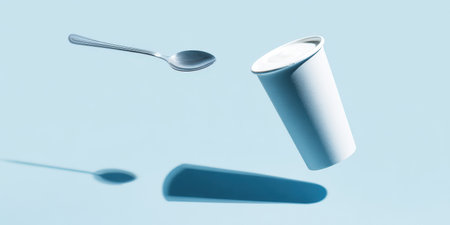 White yogurt cup and a stainless steel spoon are levitating over a light blue surface, casting long shadows, symbolizing healthy breakfast, balance, and modern minimalismの素材