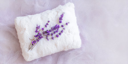 Lavender flowers presenting a calming aromatherapy and spa concept, resting on a clean, soft white towel with a light purple background, symbolizing relaxation and natural wellnessの素材
