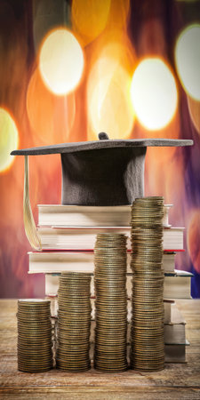 Graduation cap atop stacked books with rising columns of coins, illustrating rising tuition, student debt and the financial burden of pursuing a college degree and future successの素材