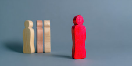 Distinct red wooden figure stands separated from a group of three beige wooden figures, representing concepts of leadership, individuality, and differentiation from the backgroundの素材