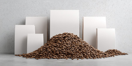 Heap of roasted coffee beans standing on a concrete counter, with various blank white product packaging bags arranged against a light grey concrete wall, creating a clean branding mockupの素材