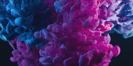 Vibrant blue and magenta ink diffusing and swirling underwater against a dark background, creating dynamic abstract patterns and fluid shapes, illustrating artistic chemistry and colorful motionの素材