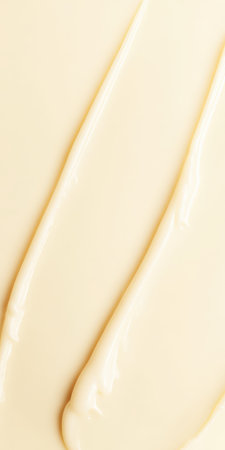 Creamy light yellow cosmetic product spreading on a background, showing thick texture and smooth strokes of lotion for skincare treatments and beauty conceptsの素材