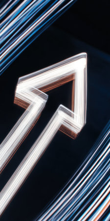 Abstract light painting creating a dynamic upward arrow symbol, representing progress, growth, and directional movement against a dark background with blurred light trailsの素材