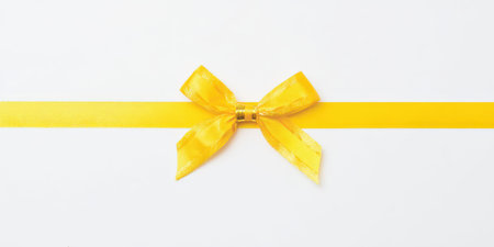 Yellow satin ribbon with a decorative bow on a pristine white background, symbolizing gifts, celebrations, anniversaries, and special moments for various holidays and occasionsの素材
