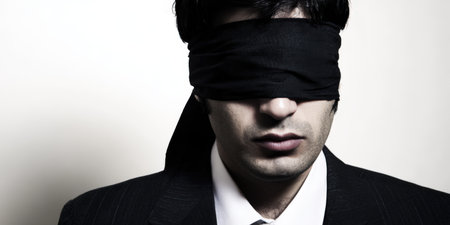 Businessman wearing a black blindfold, representing themes of ignorance, blind trust, hidden facts, censorship, business risk, and a lack of clear visionの素材
