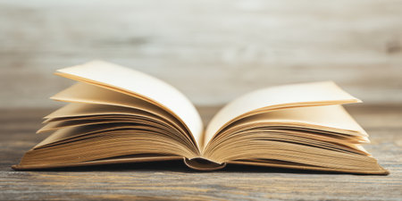 Open book with aged blank pages displaying a vintage feel, resting on a rustic wooden table with a light wood background, representing knowledge, education, and storytellingの素材