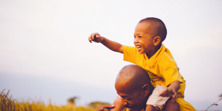 Father giving a piggyback ride to his happy son on shoulders against an outdoor background, symbolizing family bonding, joy, and a loving relationship between parent and childの素材