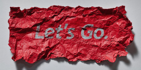 Red crumpled paper displaying the motivational phrase let's go, symbolizing new beginnings, determination, initiative, and the drive to start an action or journeyの素材