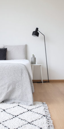 Modern bedroom interior featuring clean, minimalist design with a light wooden floor, white walls, and cozy scandinavian-style bedding, creating a tranquil and comfortable home environmentの素材