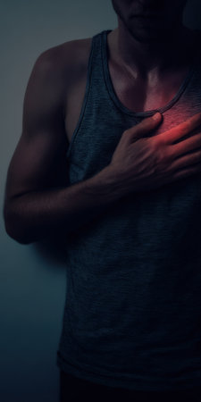 Man clutching his chest in pain, symbolizing a heart attack, cardiovascular issues, or intense discomfort, highlighting health concerns and medical emergenciesの素材