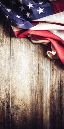 United states flag with stars and stripes displaying patriotism, national pride, and freedom, draped over distressed vertical natural wood planks creating a vintage backgroundの素材
