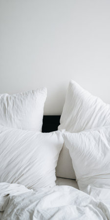 Unmade bed featuring crumpled white linen pillows and duvet, creating a cozy and inviting atmosphere for relaxation and comfort in a minimalist bedroomの素材