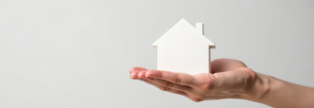 Real estate agent is holding small house model in open palm, offering property or investment opportunity in residential market, with copy space for bannerの素材