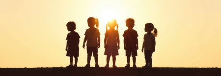 Five joyful children silhouettes standing together on a hilltop at sunset, with a vibrant sky painted in orange and gold, creating a spacious banner area above for textの素材