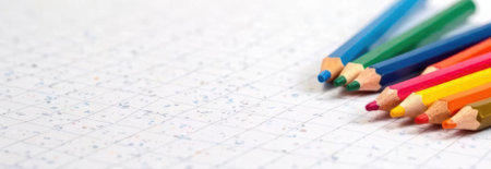 Colorful pencils lying on graph paper providing ample copy space, perfect for back to school or educational projectsの素材