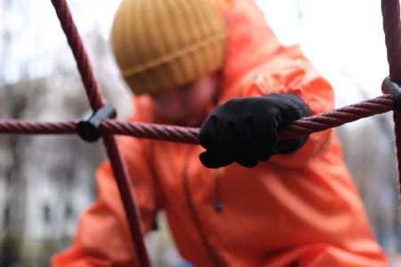 Child climbing rope structure on winter playgroundの写真素材