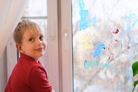 Young boy smiling creating window drawing artの写真素材