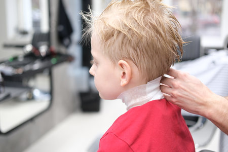 Little boy receiving preparing for a haircut in barbershopの写真素材