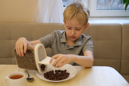 Boy pouring chocolate cereal for breakfastの写真素材