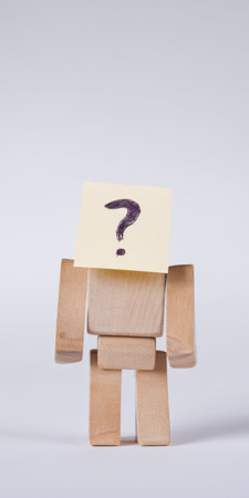 Wooden mannequin with a yellow sticky note over its face hand-drawn with a question mark, representing identity confusion, anonymity, uncertainty and searching for answersの素材