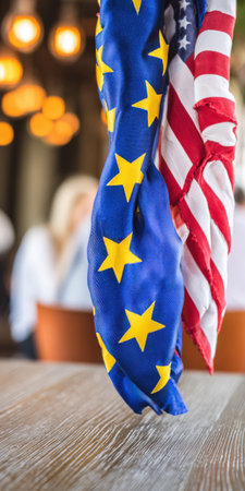 Eu and us flags hanging together, symbolizing diplomacy, geopolitical alliance, and partnership between the European union and the united states in a blurred interior settingの素材