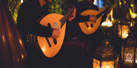 Musicians perform traditional Arabic oud music by lantern and candlelight at night, creating a warm, atmospheric scene evoking middle eastern cultural celebration and heritageの素材