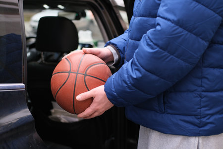 Close-up of man holding basketball near car
