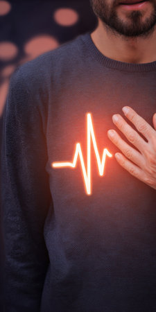 Man placing hand on chest with glowing electrocardiogram heartbeat line on sweater, symbolizing heart health, cardiology care, vitality, monitoring, prevention, and medical checkupの素材